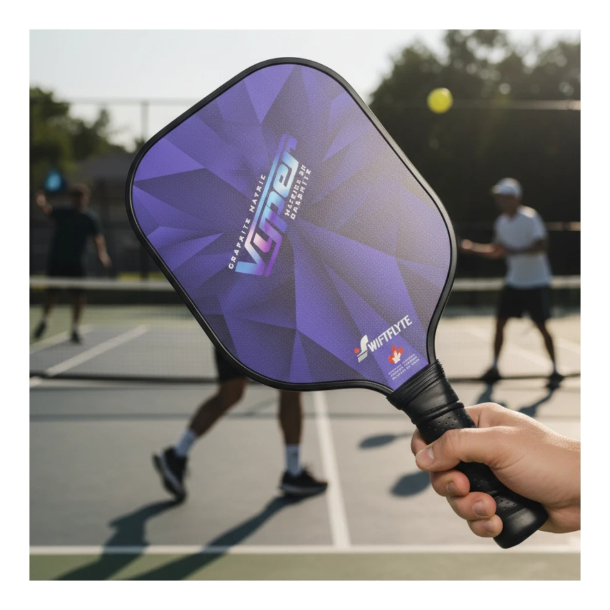 Full view of Swiftflyte Vyper Pickleball Paddle held by a hand with people playing pickleball in the background