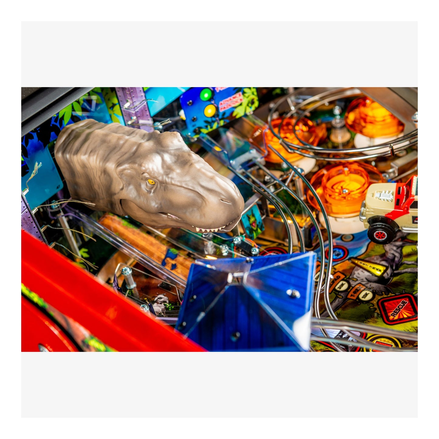 Close-up of a pinball machine with a dinosaur head figure and colorful playfield.