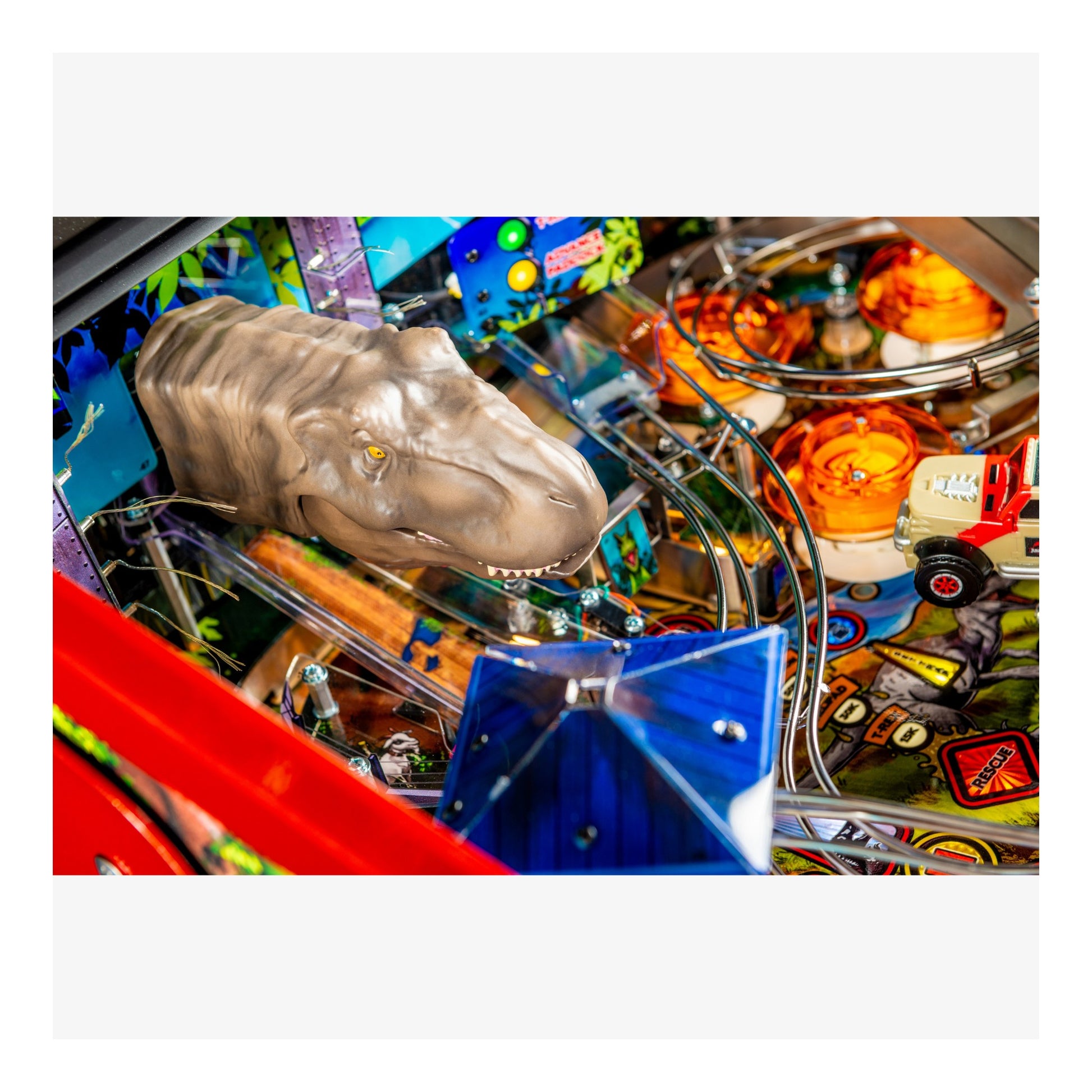 Close-up of a pinball machine with a dinosaur head figure and colorful playfield.