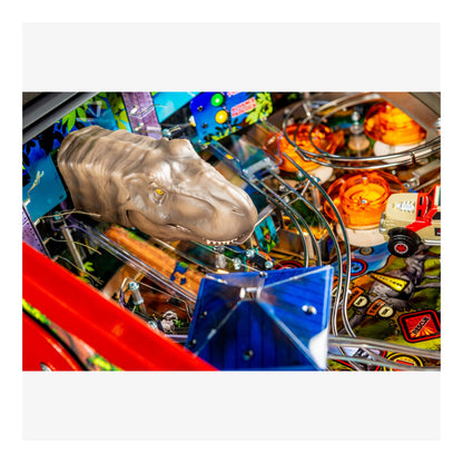 Close-up of a pinball machine with a dinosaur head figure and colorful playfield.