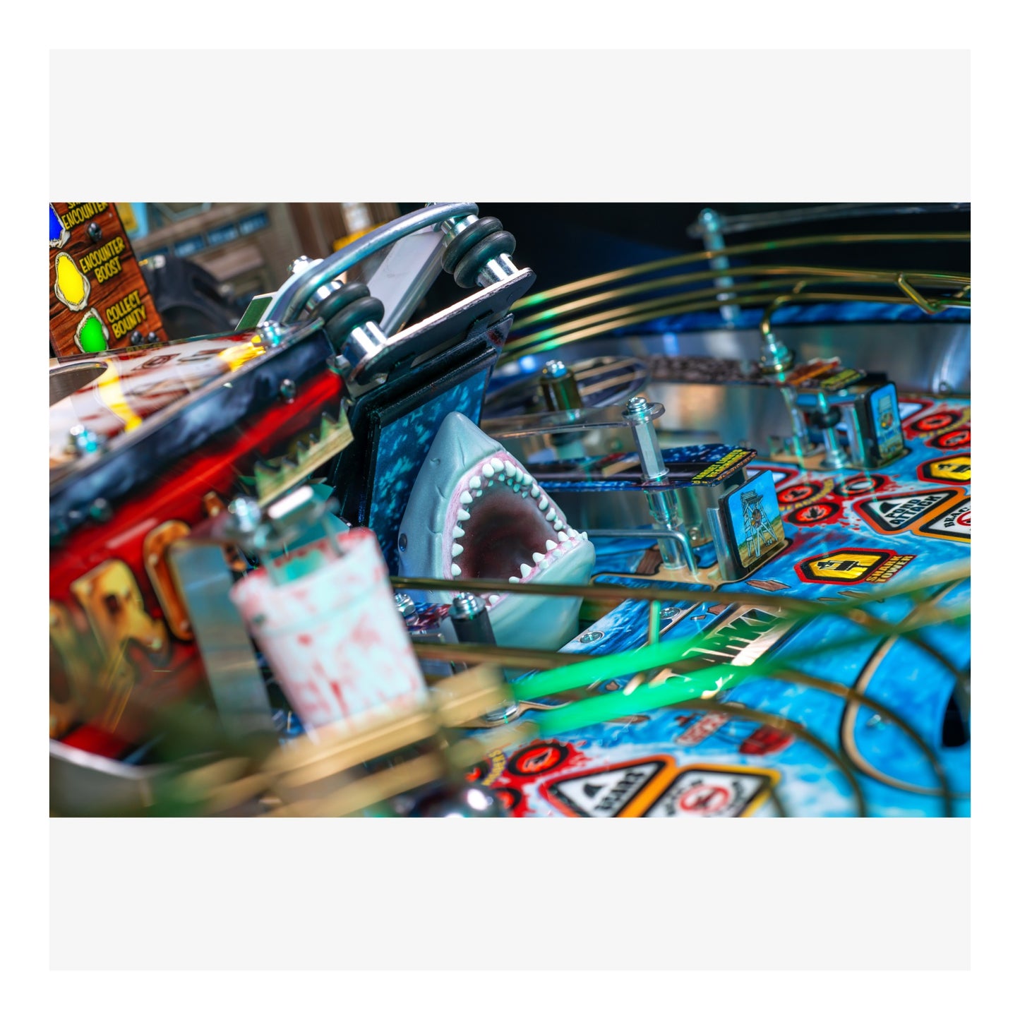 Close-up of a pinball machine with a shark figure and colorful playfield.