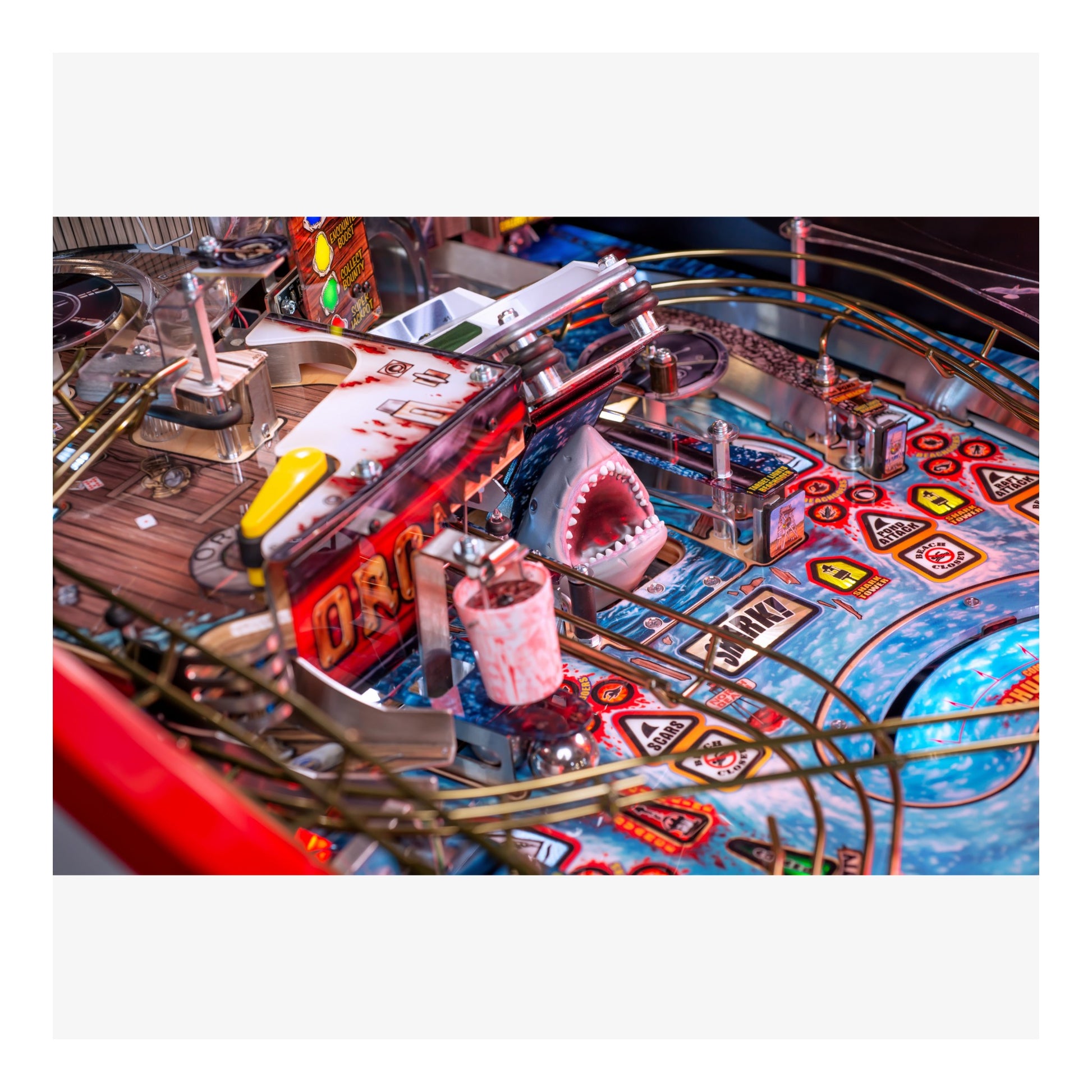 Close-up of a pinball machine with a shark figure and colorful design.