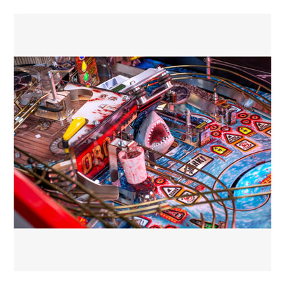 Close-up of a pinball machine with a shark figure and colorful design.