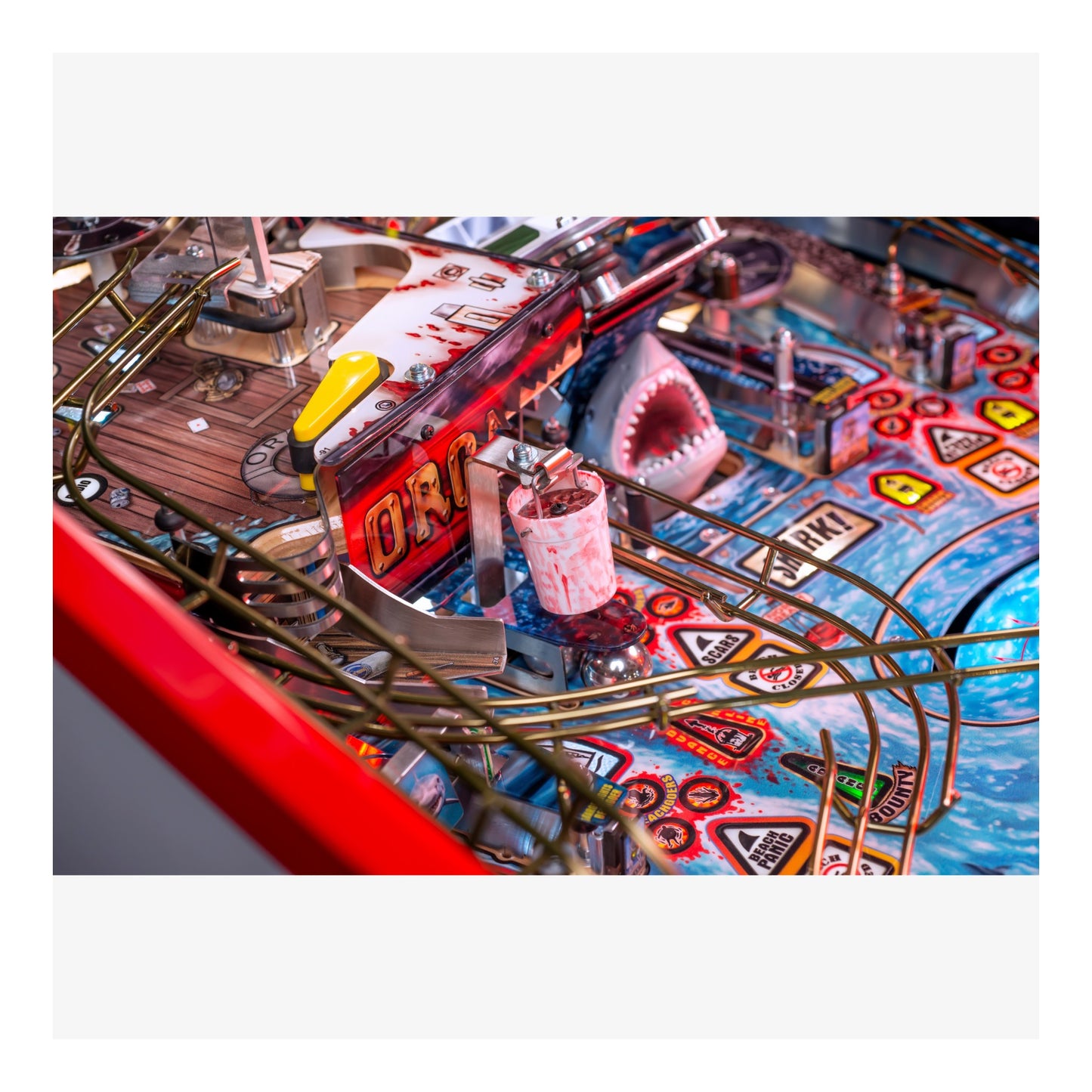 Close-up of a pinball machine with a shark figure and colorful playfield.