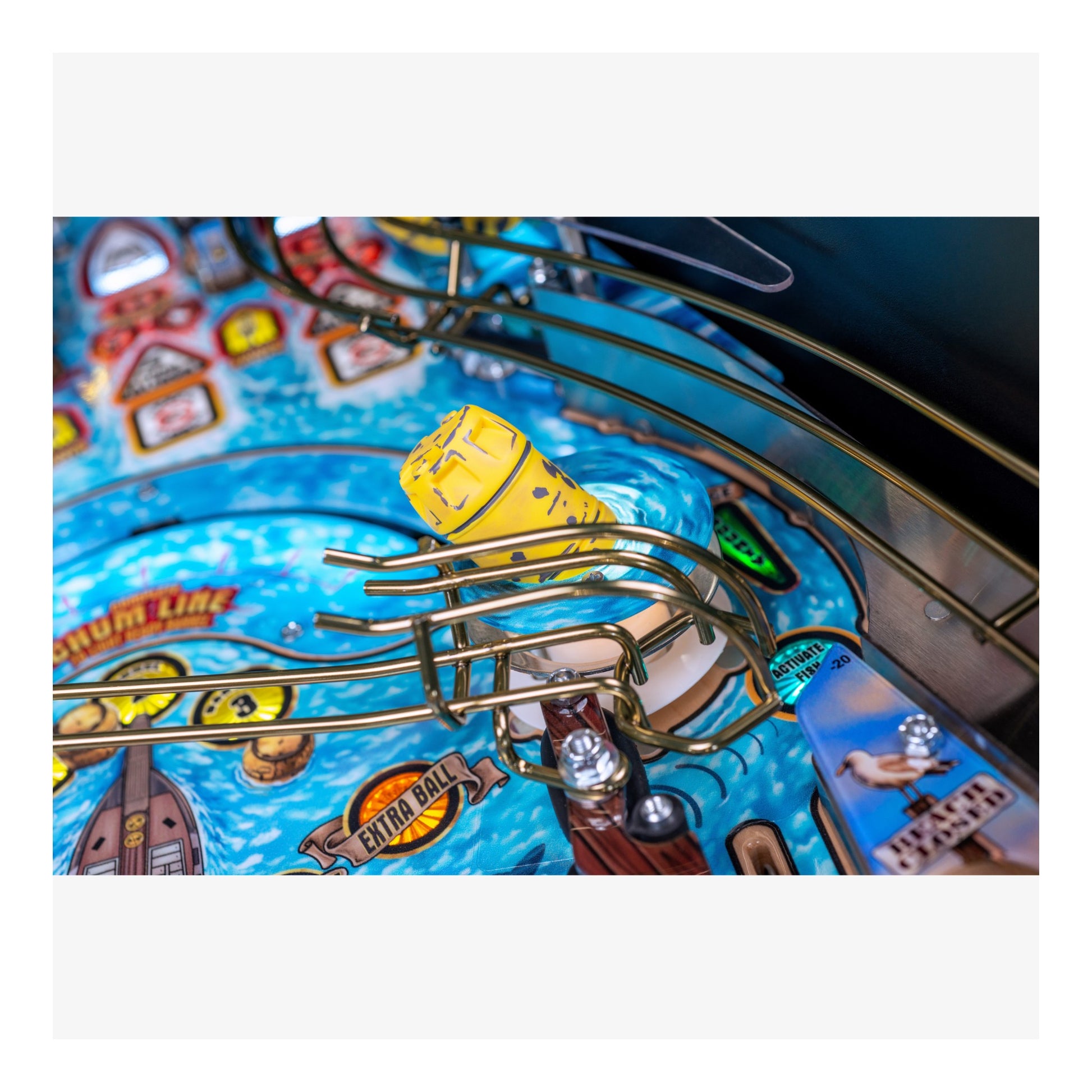 Close-up of a pinball machine with a yellow ball on a blue background