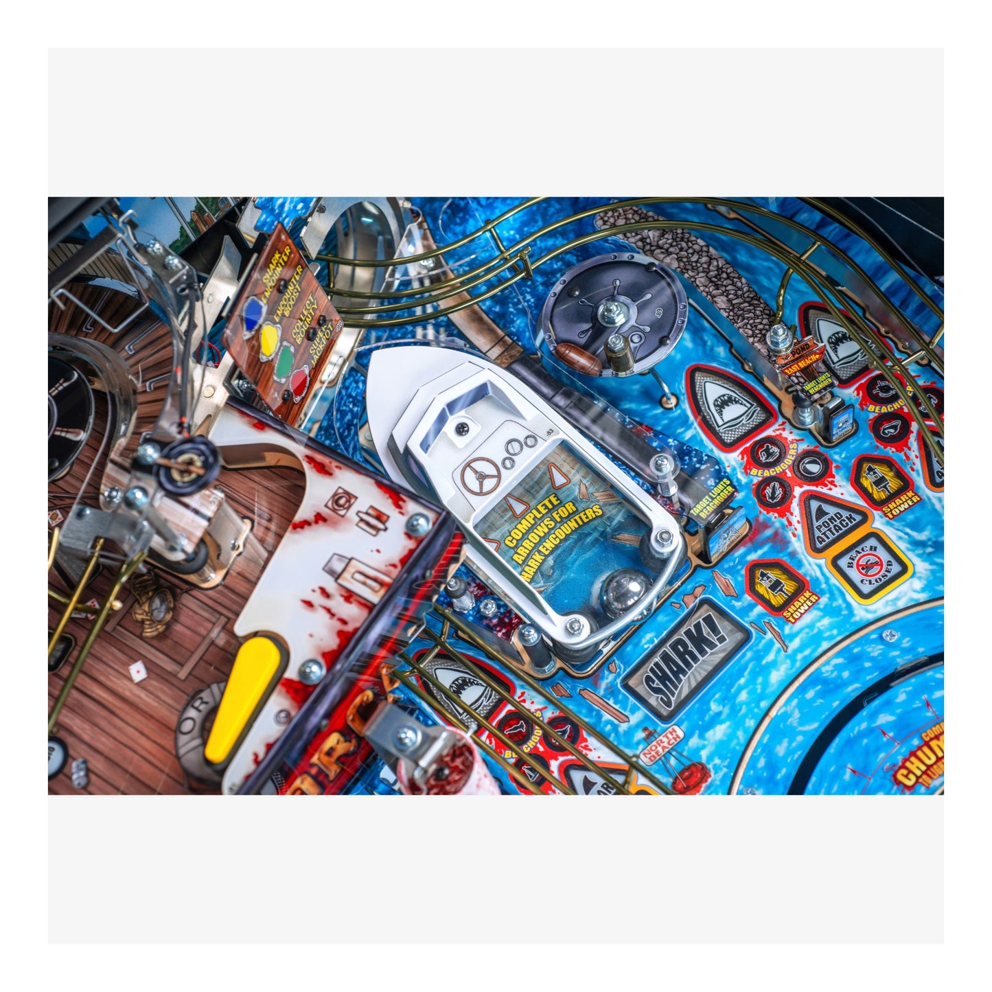 Close-up of a pinball machine with various components and a blue background