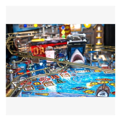 Close-up of a pinball machine with a shark design and colorful playfield.