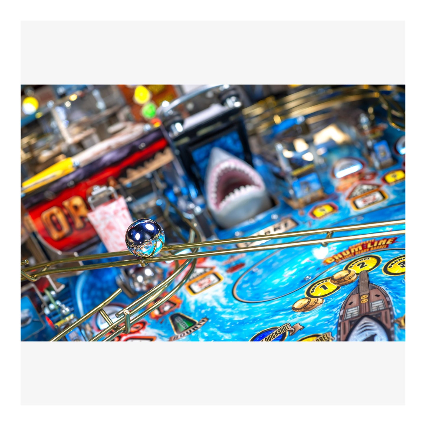 Close-up of a pinball machine with a shark figure and colorful design.