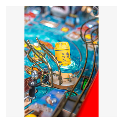 Close-up of a pinball machine with a yellow bucket and blue playing field.