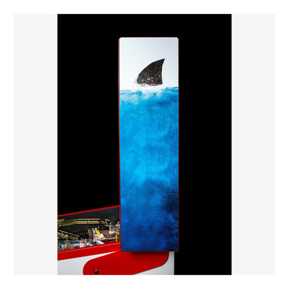Abstract artwork with a shark fin emerging from blue water, framed by black and white borders.