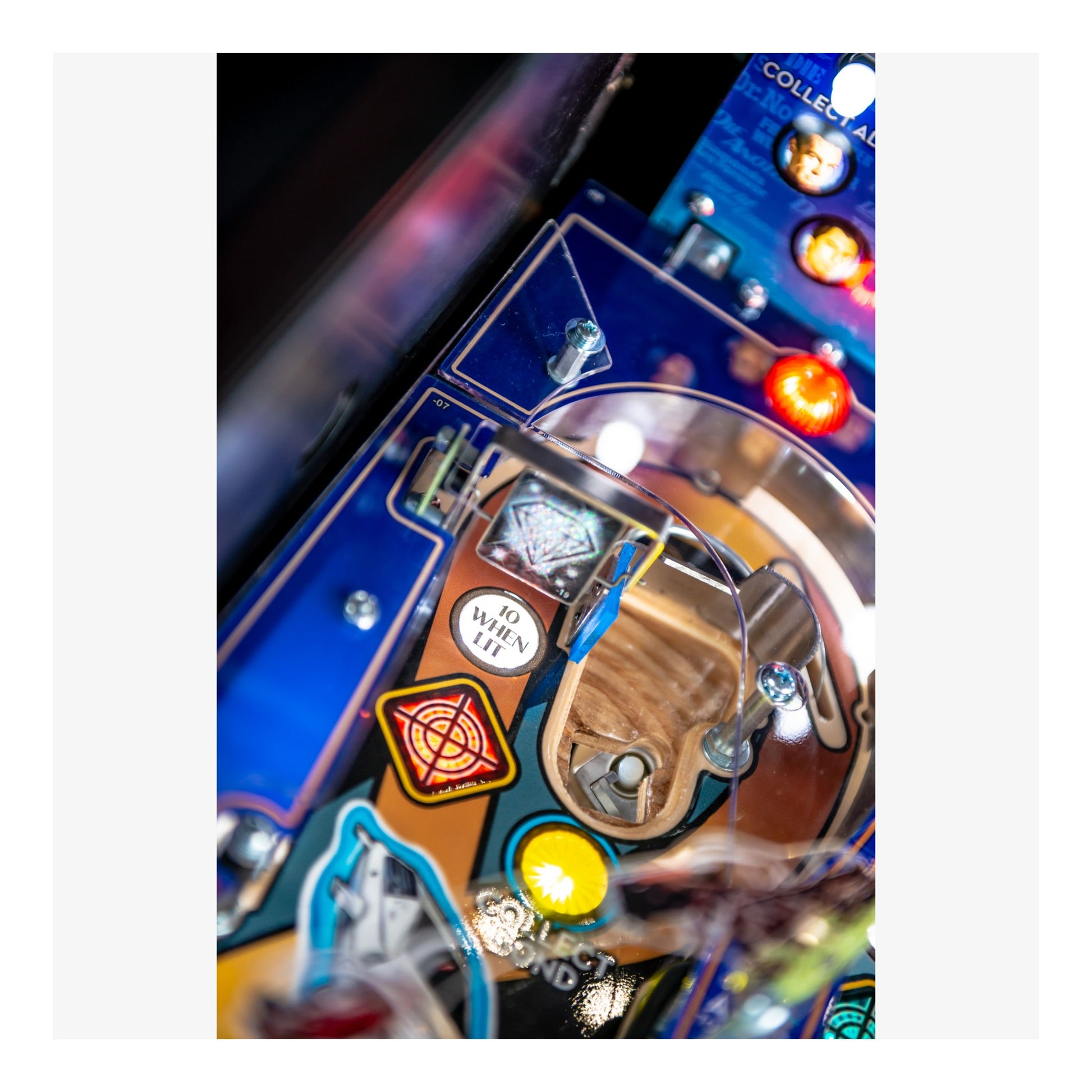 Close-up of a pinball machine's playfield with various components and lights.