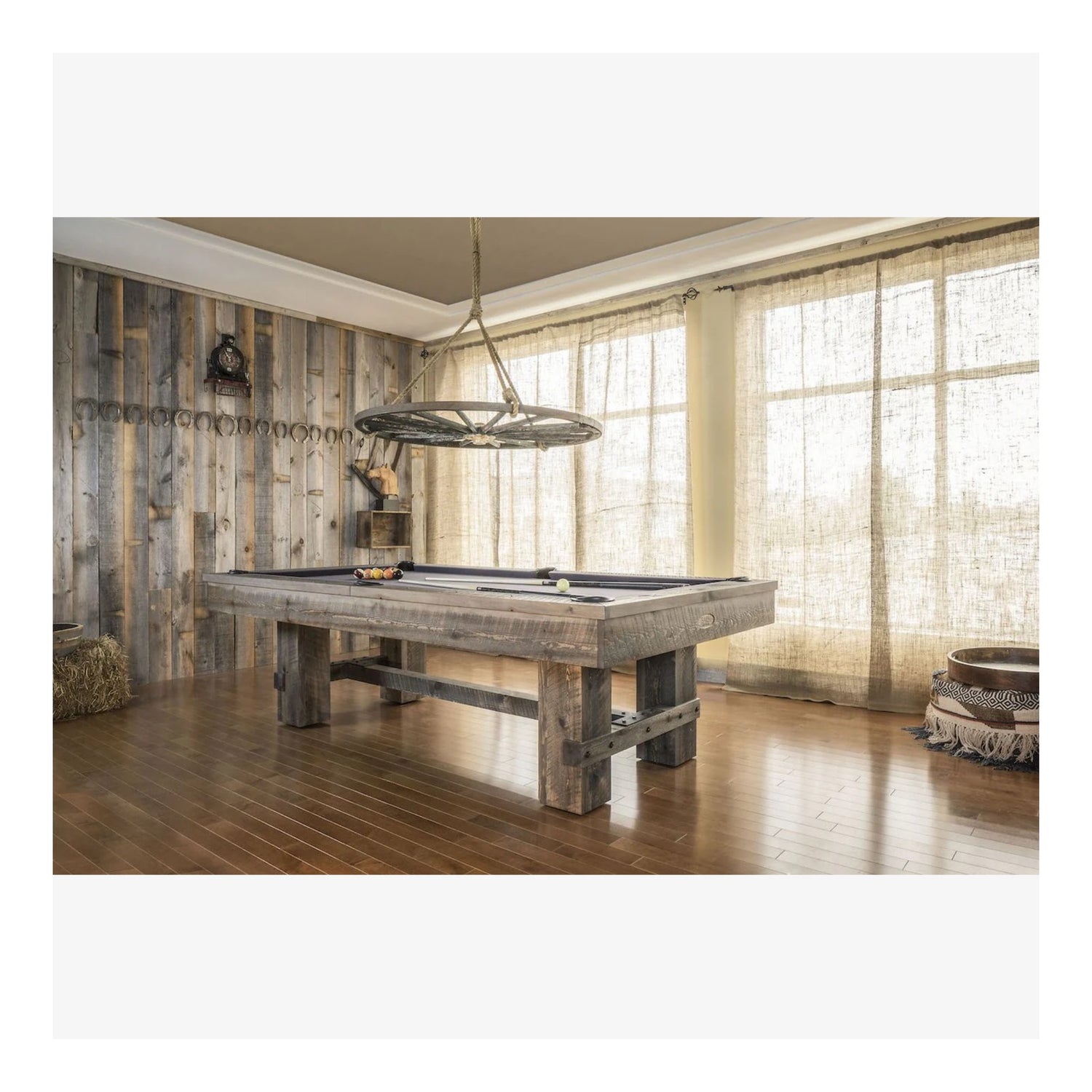 The Canada Billiard Barn pool table with an antique grey stain, shown in a rustic-style game room with a wood wall.
