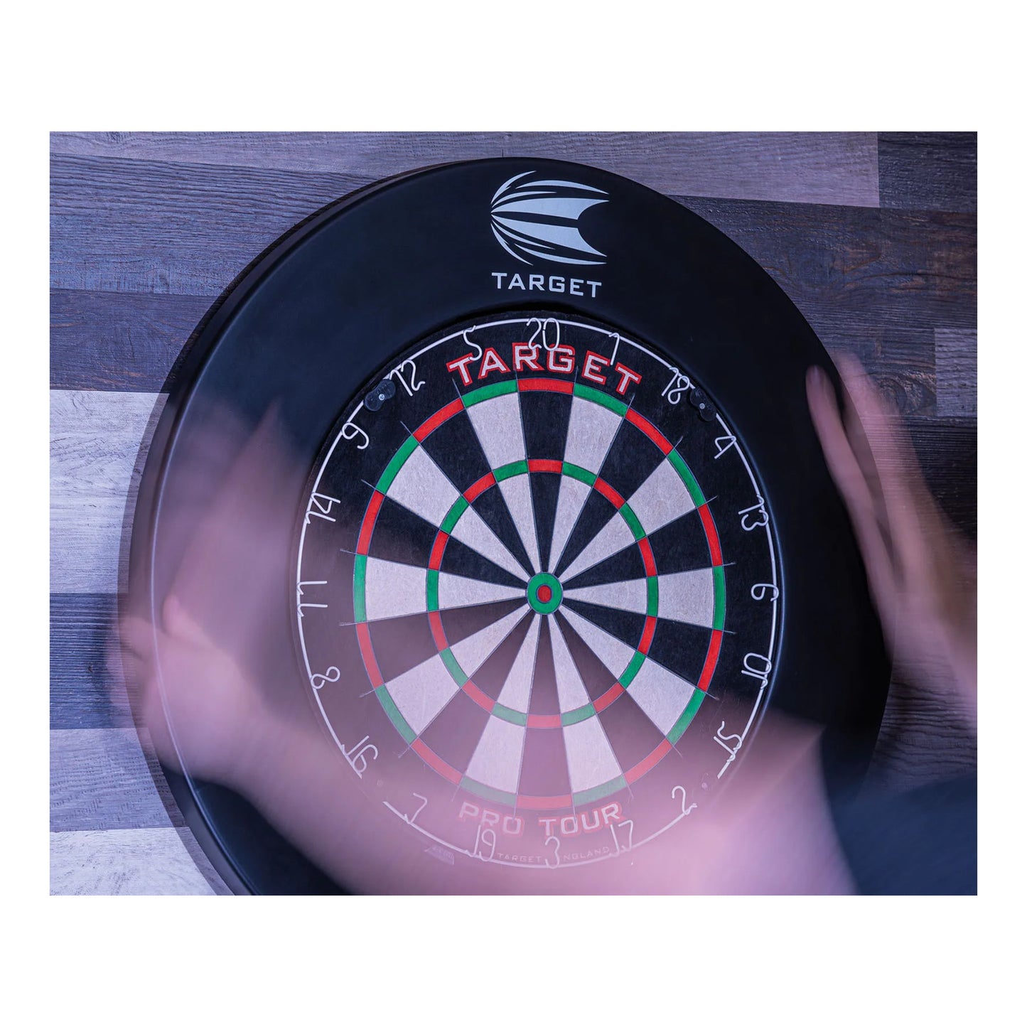 Dartboard with 'Target' branding on a wooden surface surrounded with black Pro Tour