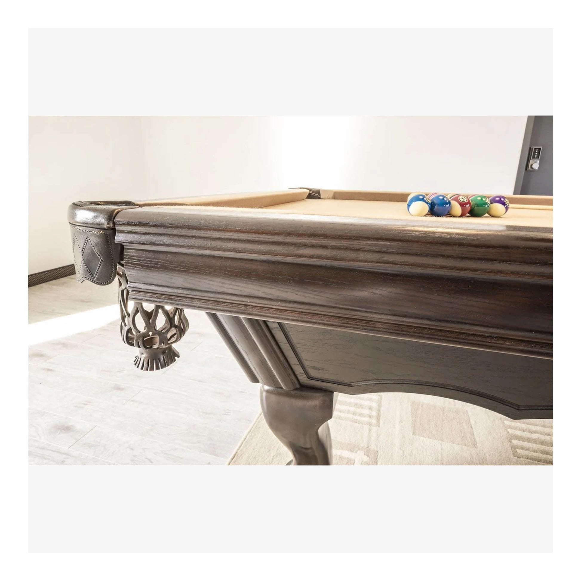 Close-up of a pool table with billiard balls on a light-colored floor.