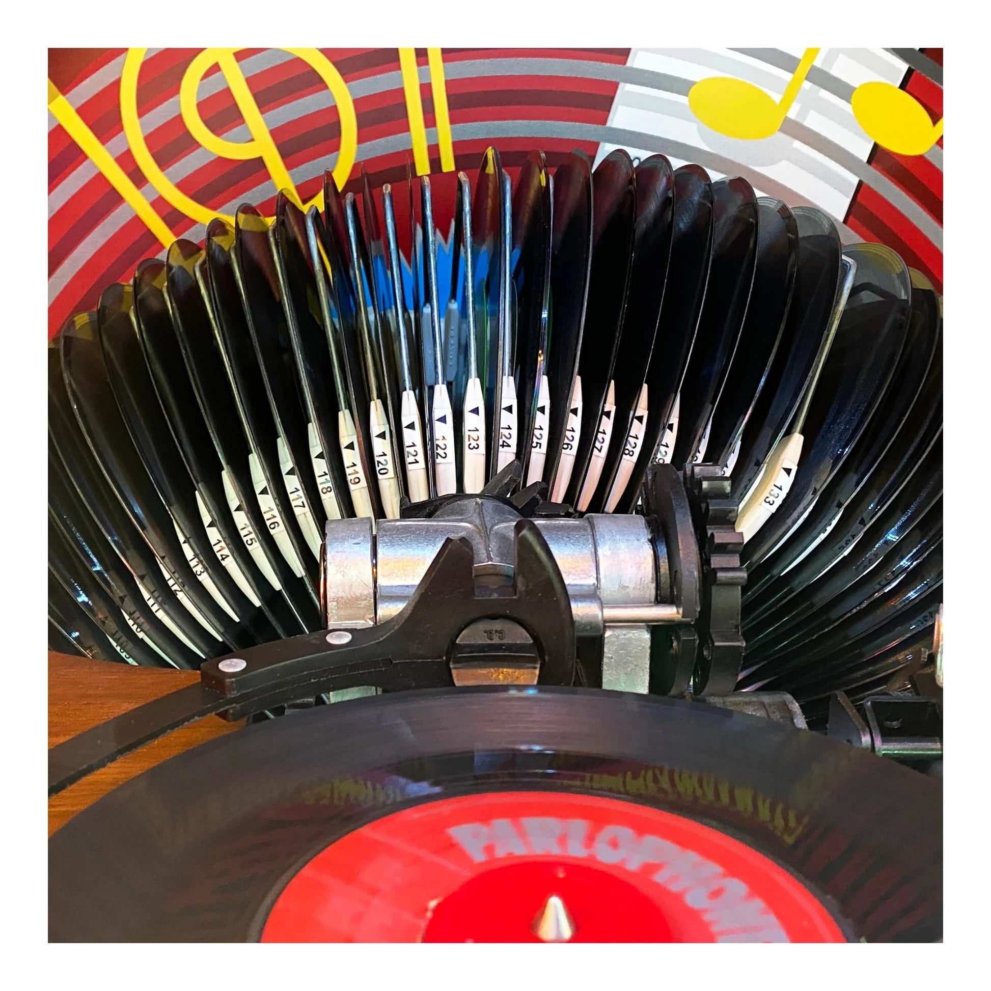 Close-up of a vinyl record player headshell with a colorful background