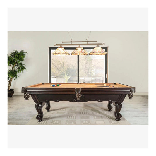 Wooden pool table with cues and balls in a room with large windows and decorative lights.