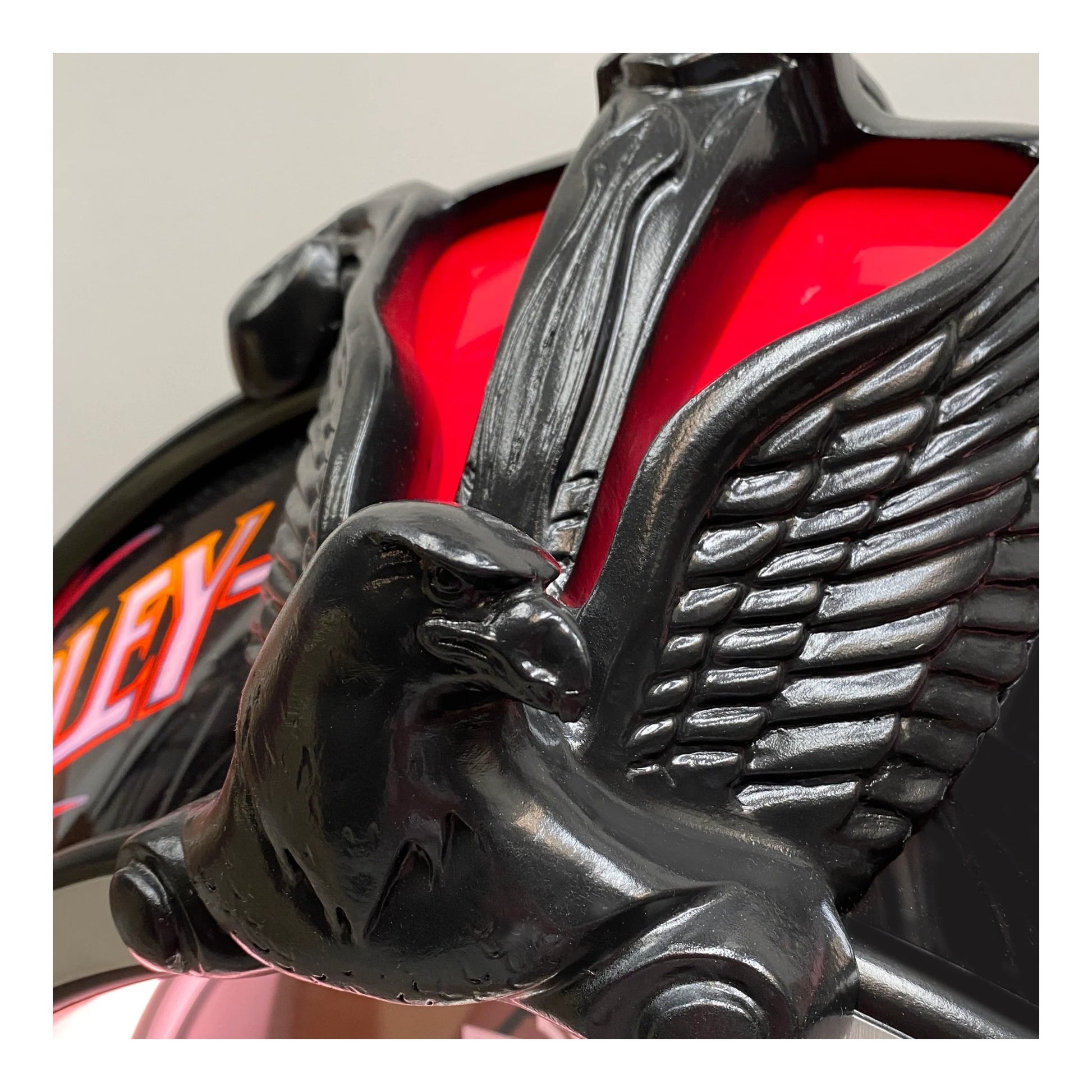 Close-up of a motorcycle with an eagle emblem on a red background
