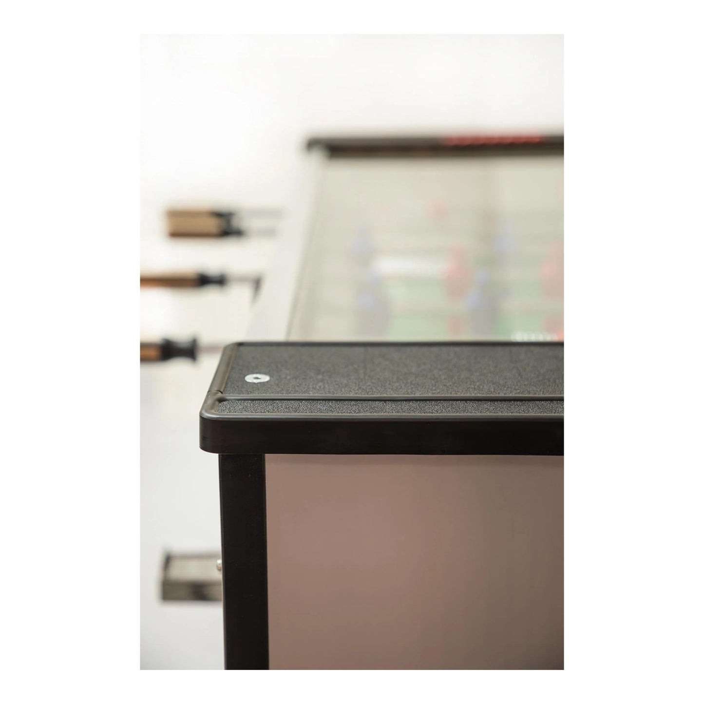 Close-up of a black foosball cabinet corner with a blurred background