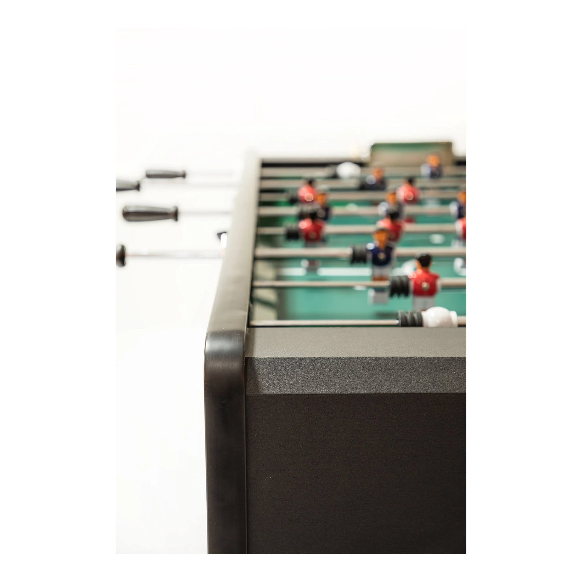 Close-up of a foosball table with players and rods on a white background