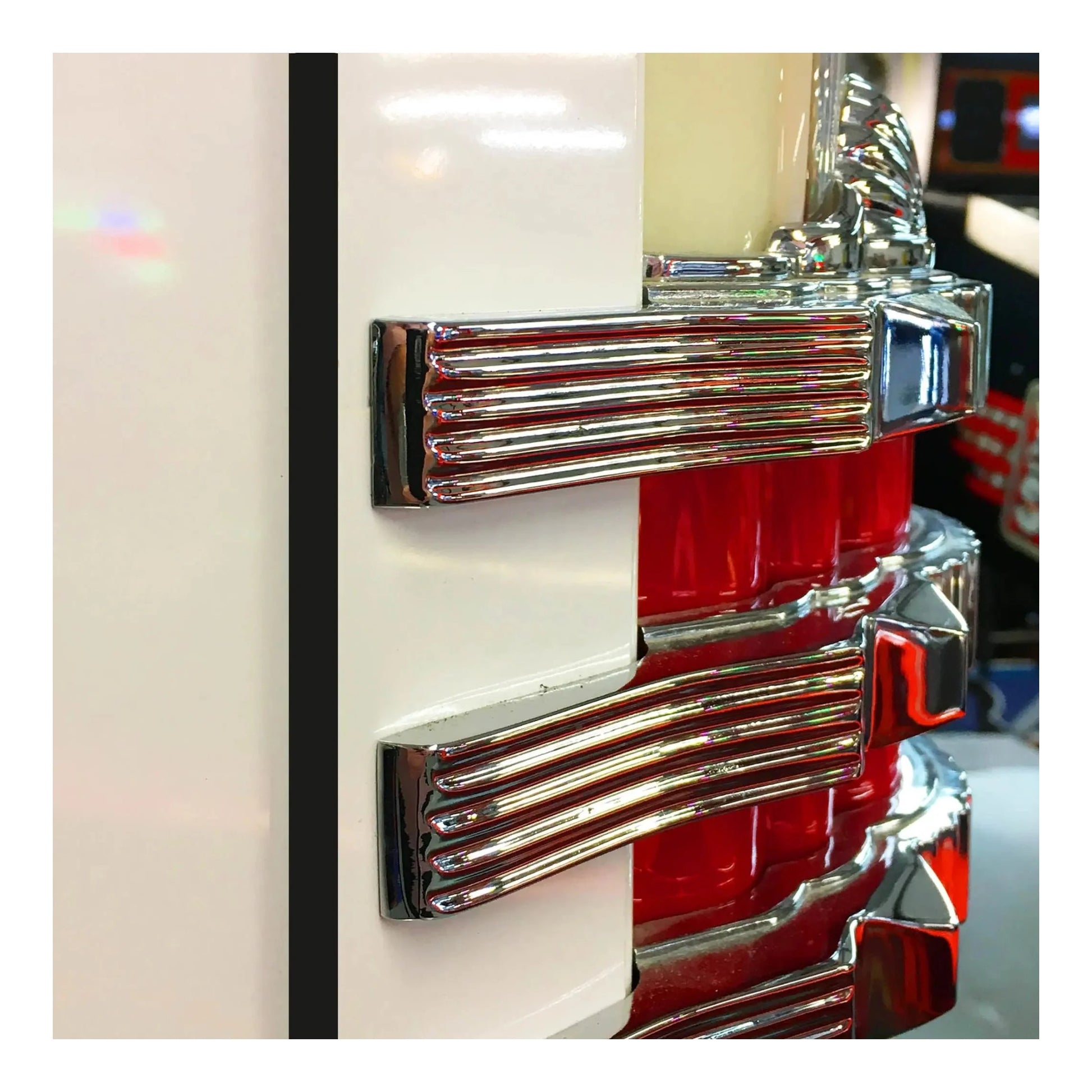 Close-up of a red and chrome jukebox emblem on a white background