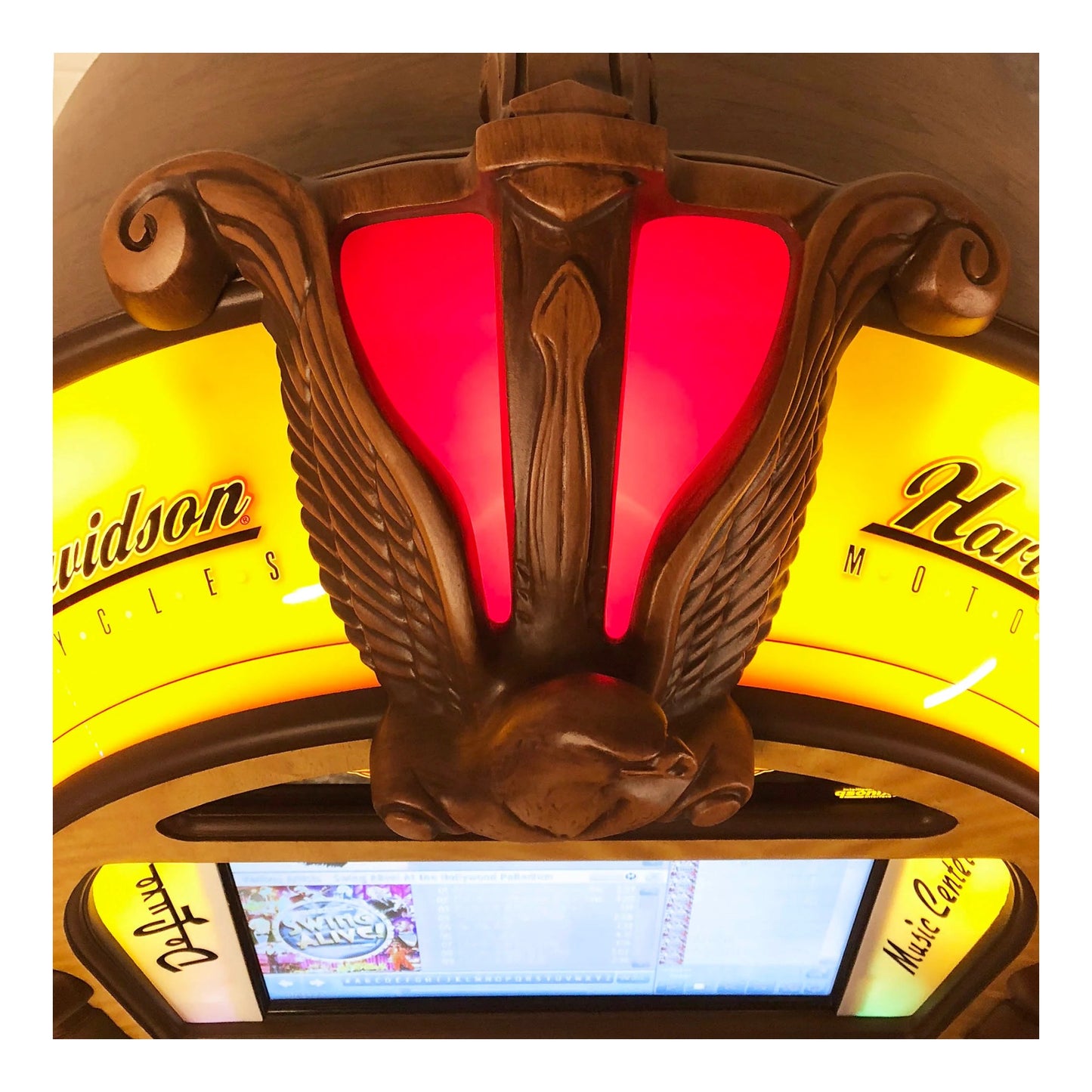 Decorative light fixture with red center and yellow sides featuring brand names.