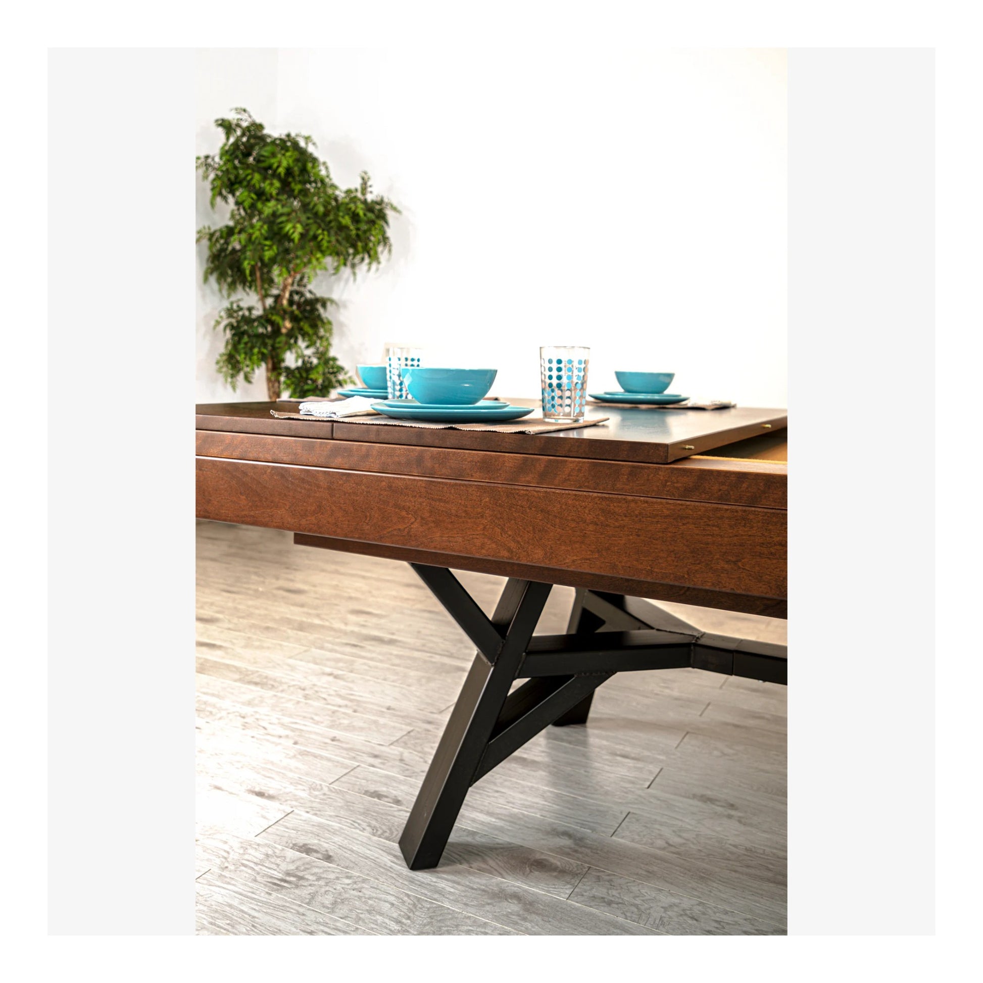 Dining table set with blue dishes and glasses on a wooden floor.