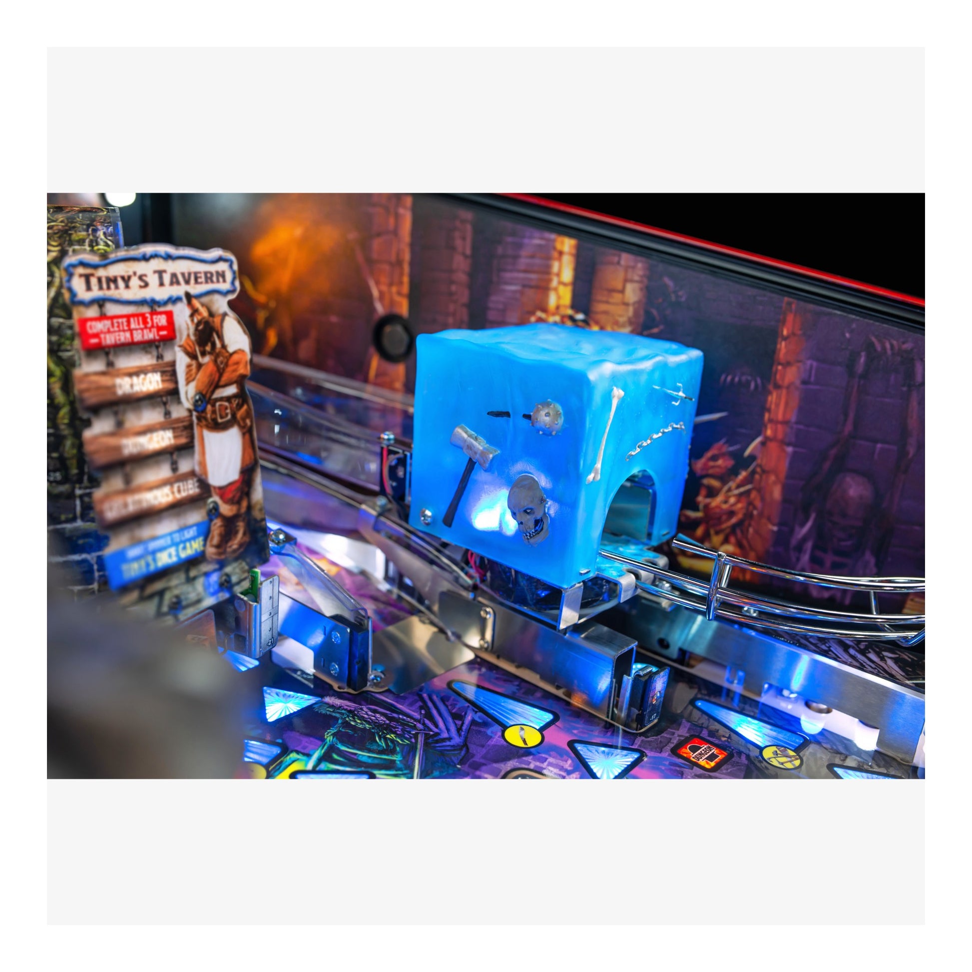 Pinball machine with a blue cube and 'Tiny's Tavern' sign in the background
