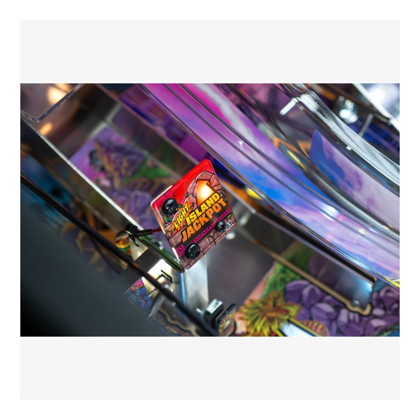 Close-up of a pinball machine with a 'Hot Land Jackpot' card on the playfield.