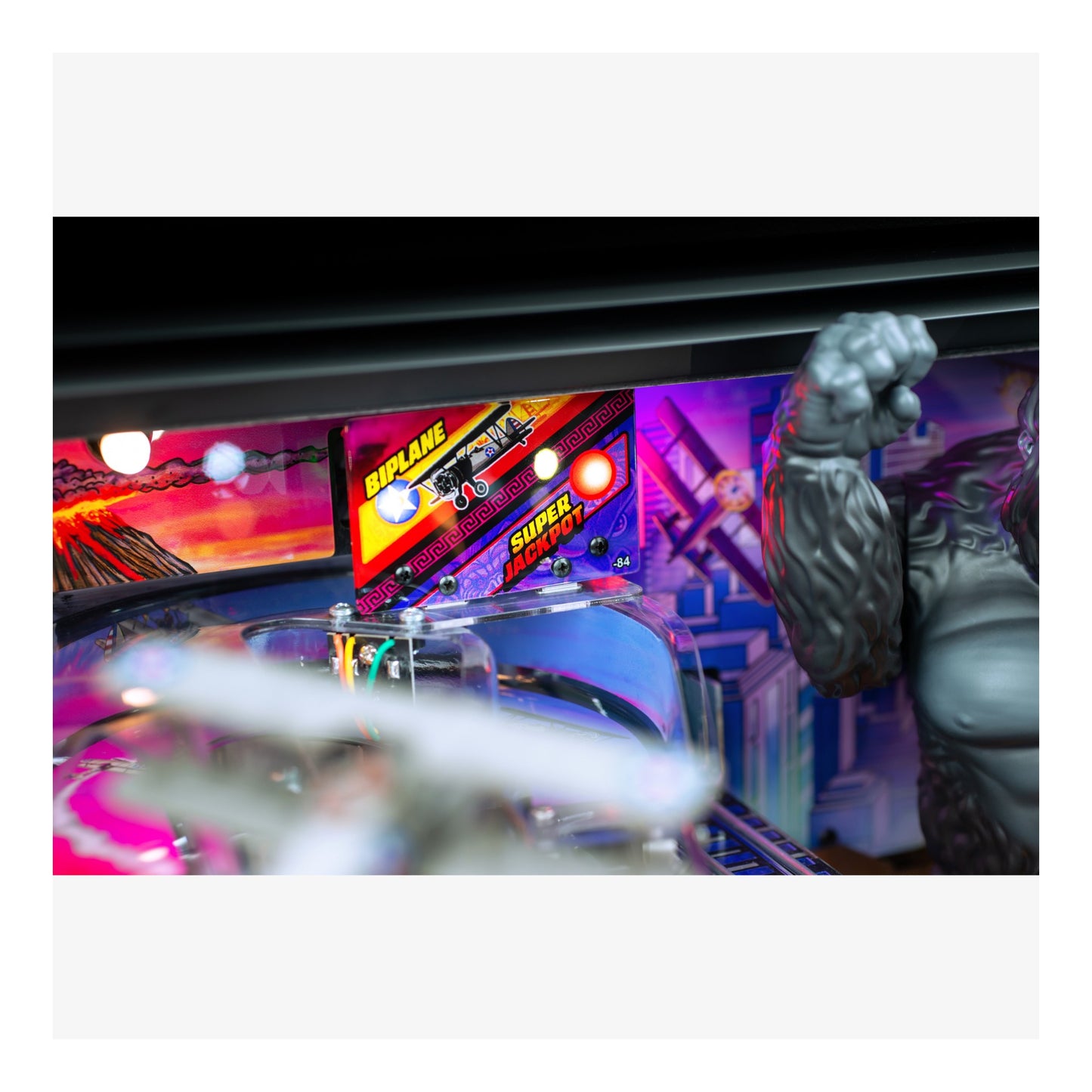 Pinball machine with colorful lights and a large fist figure on a white background