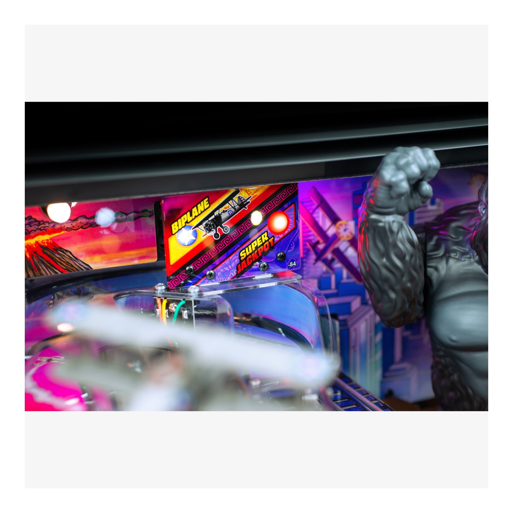 Pinball machine with colorful lights and a large fist figure on a white background