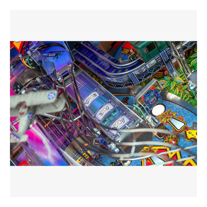 Close-up of a colorful pinball machine with various elements and a player's hand.