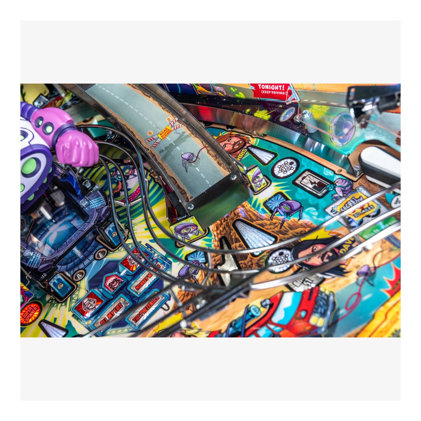 Close-up of a colorful pinball machine with various elements and a smartphone held above it.