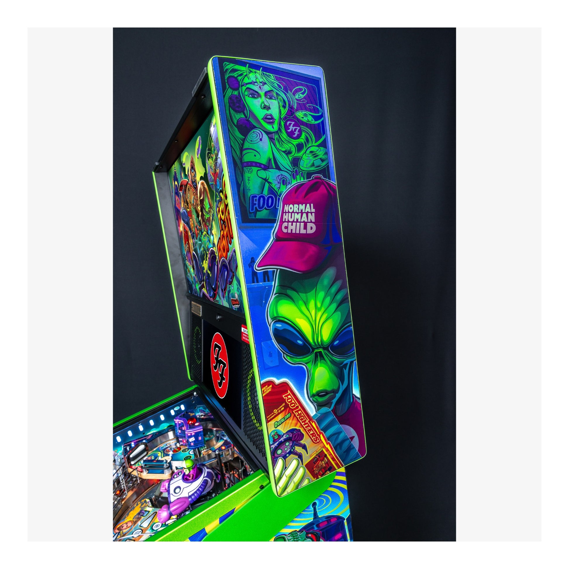 Colorful pinball machine with alien and superhero graphics on a dark background