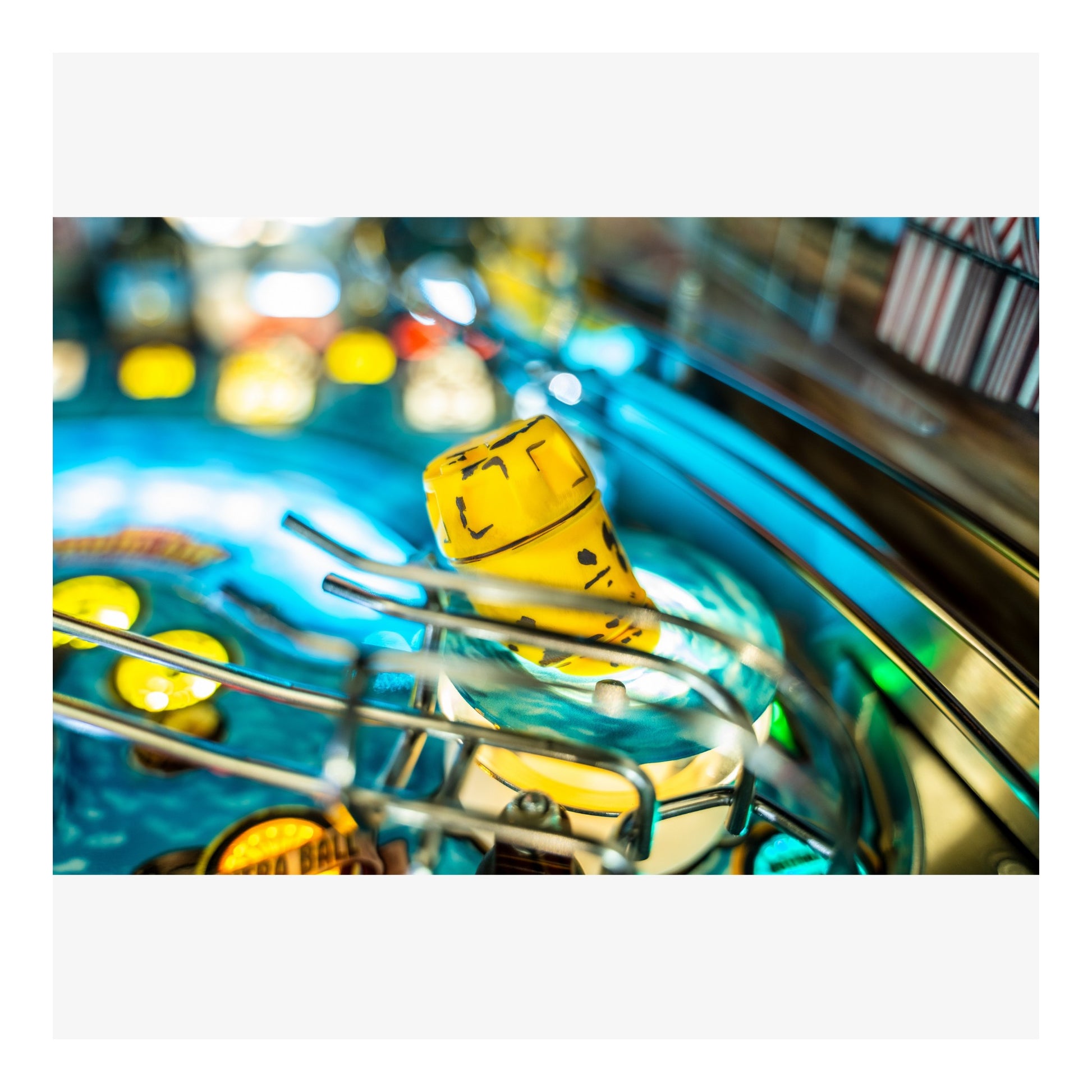 Close-up of a yellow pinball in a pinball machine with colorful lights.