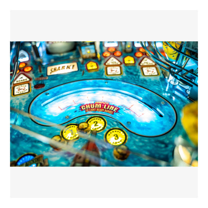Close-up of a pinball machine with colorful playfield and various buttons.