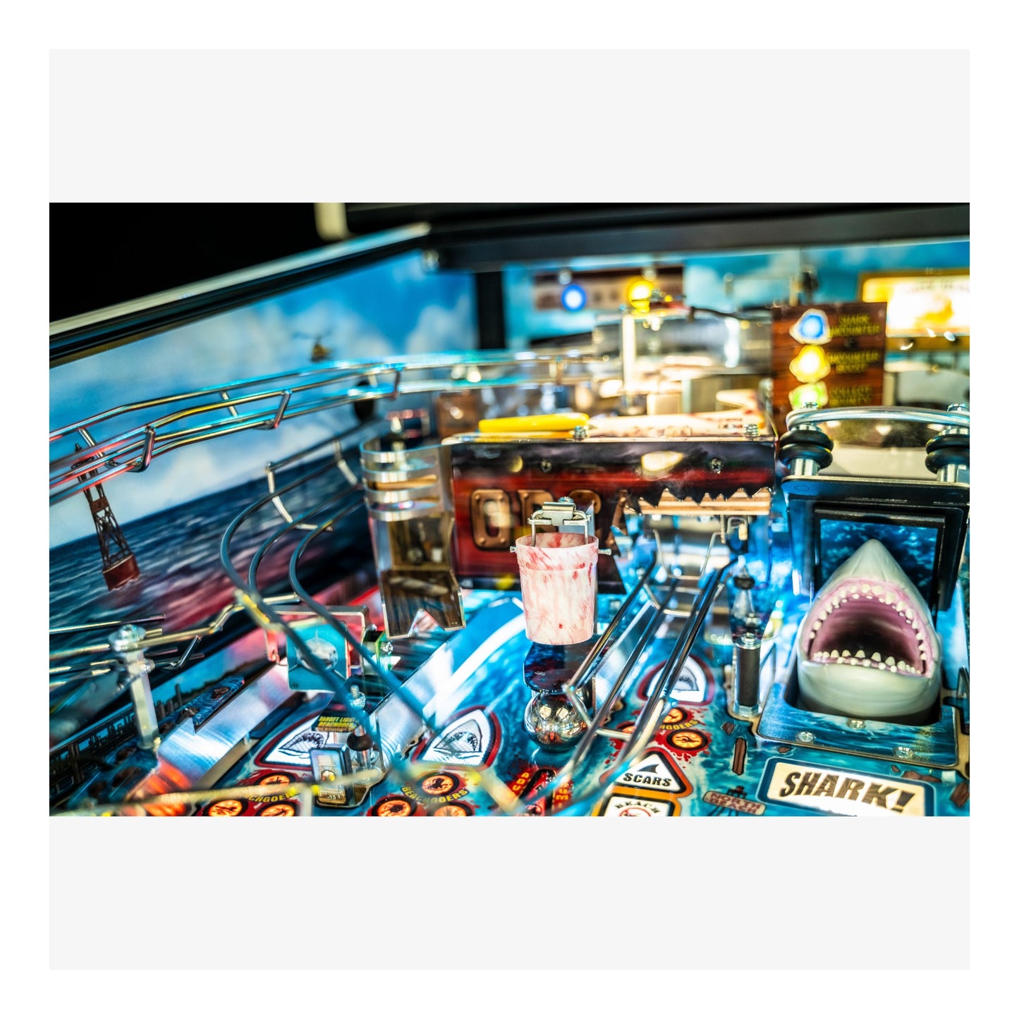 Close-up of a pinball machine with a shark figure and colorful details.