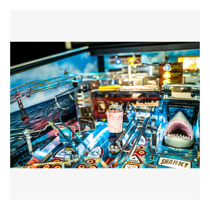 Close-up of a pinball machine with a shark figure and colorful details.
