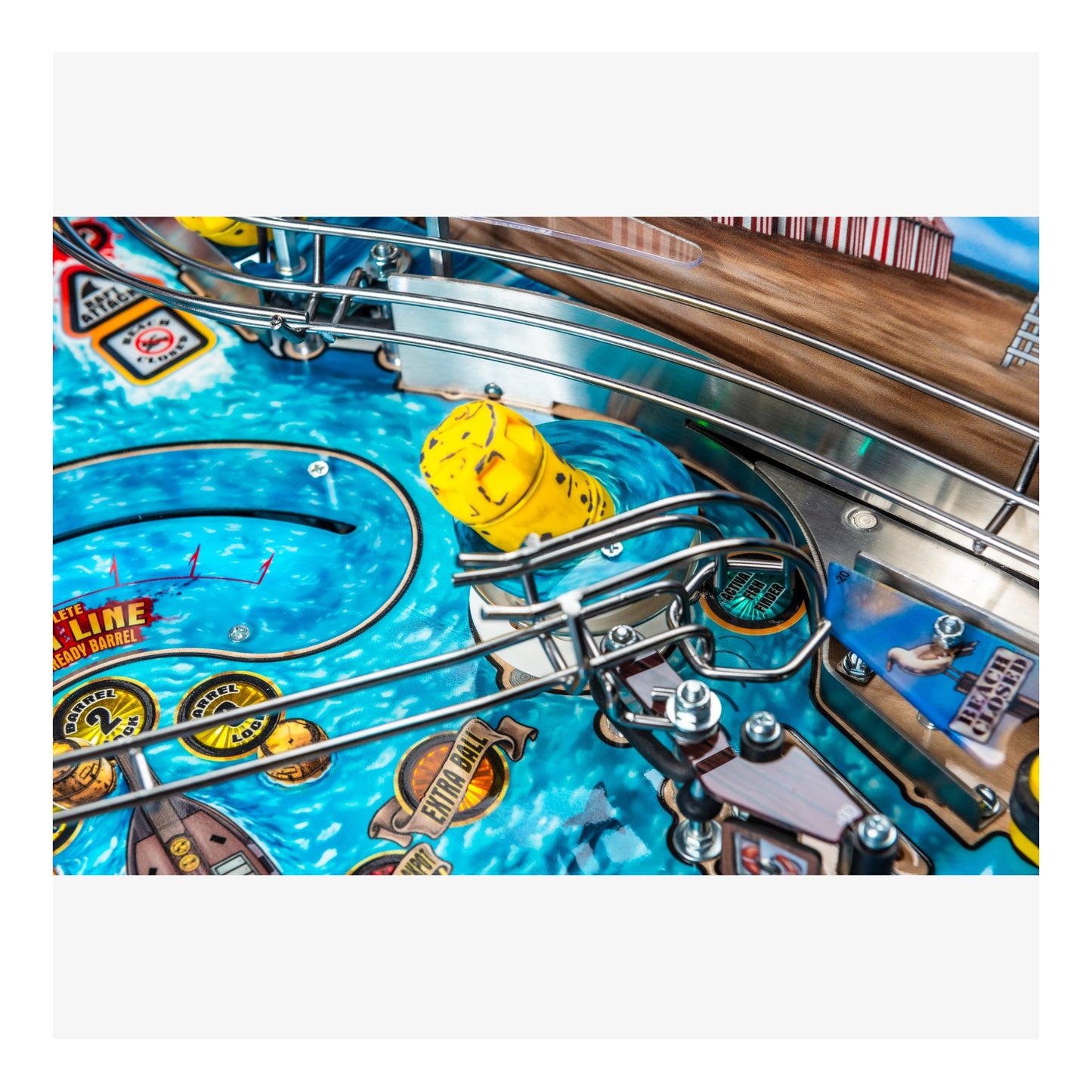 Close-up of a pinball machine with a yellow ball on a blue playing field.