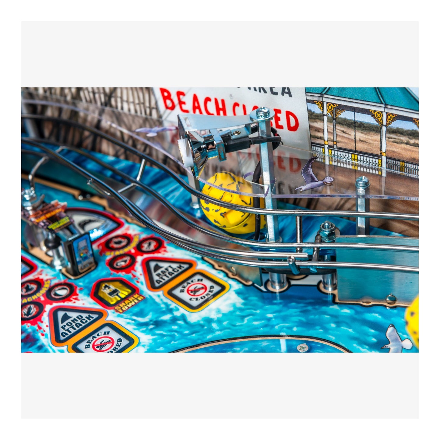 Close-up of a pinball machine with colorful design and 'Beach Closed' sign.