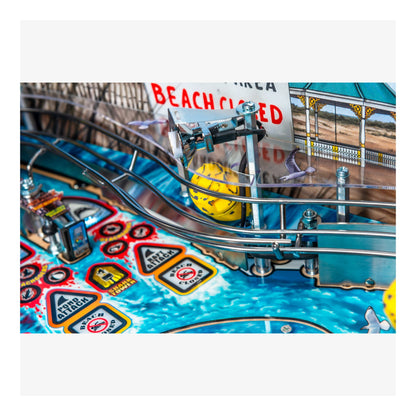 Close-up of a pinball machine with colorful design and 'Beach Closed' sign.