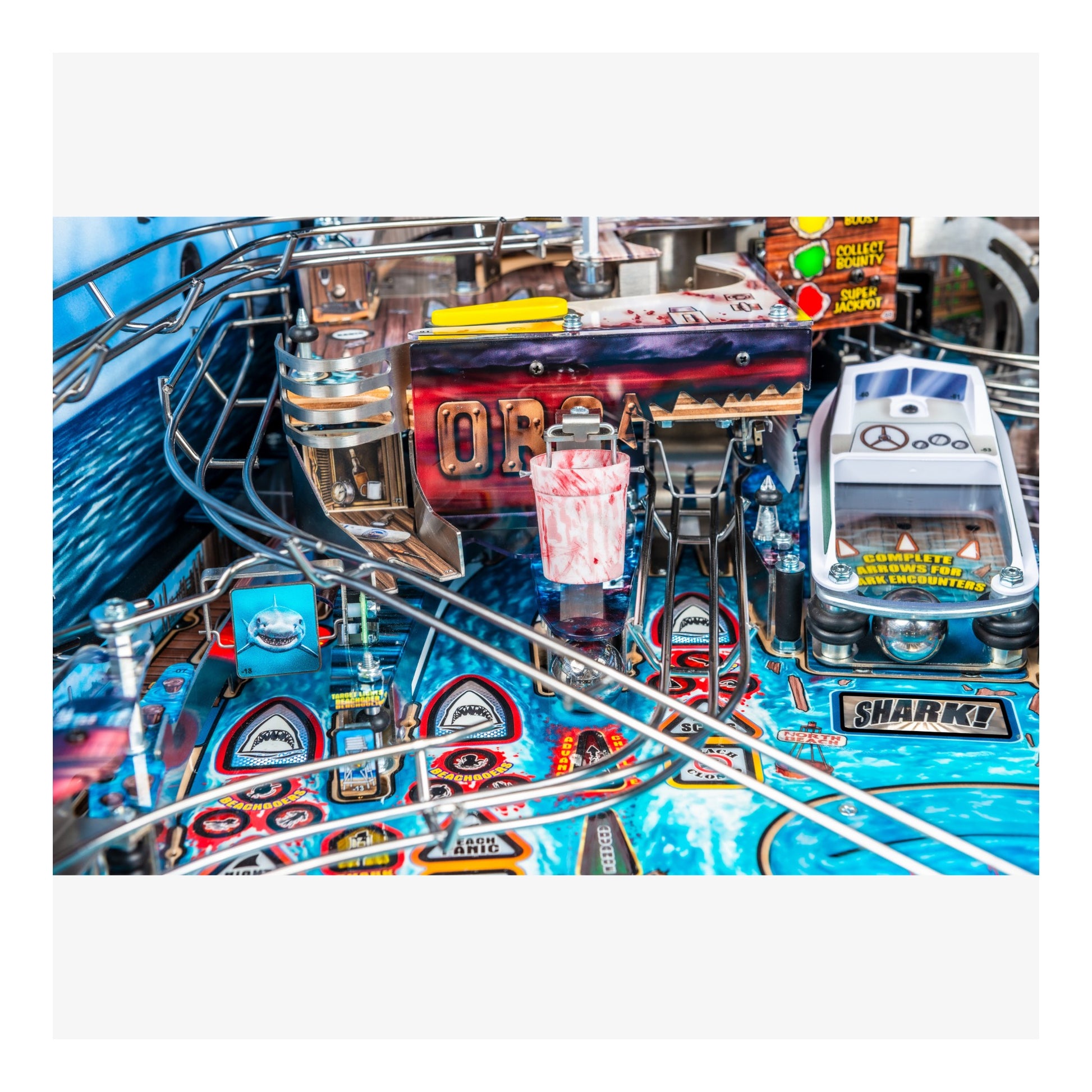 Close-up of a pinball machine with various components and branding.