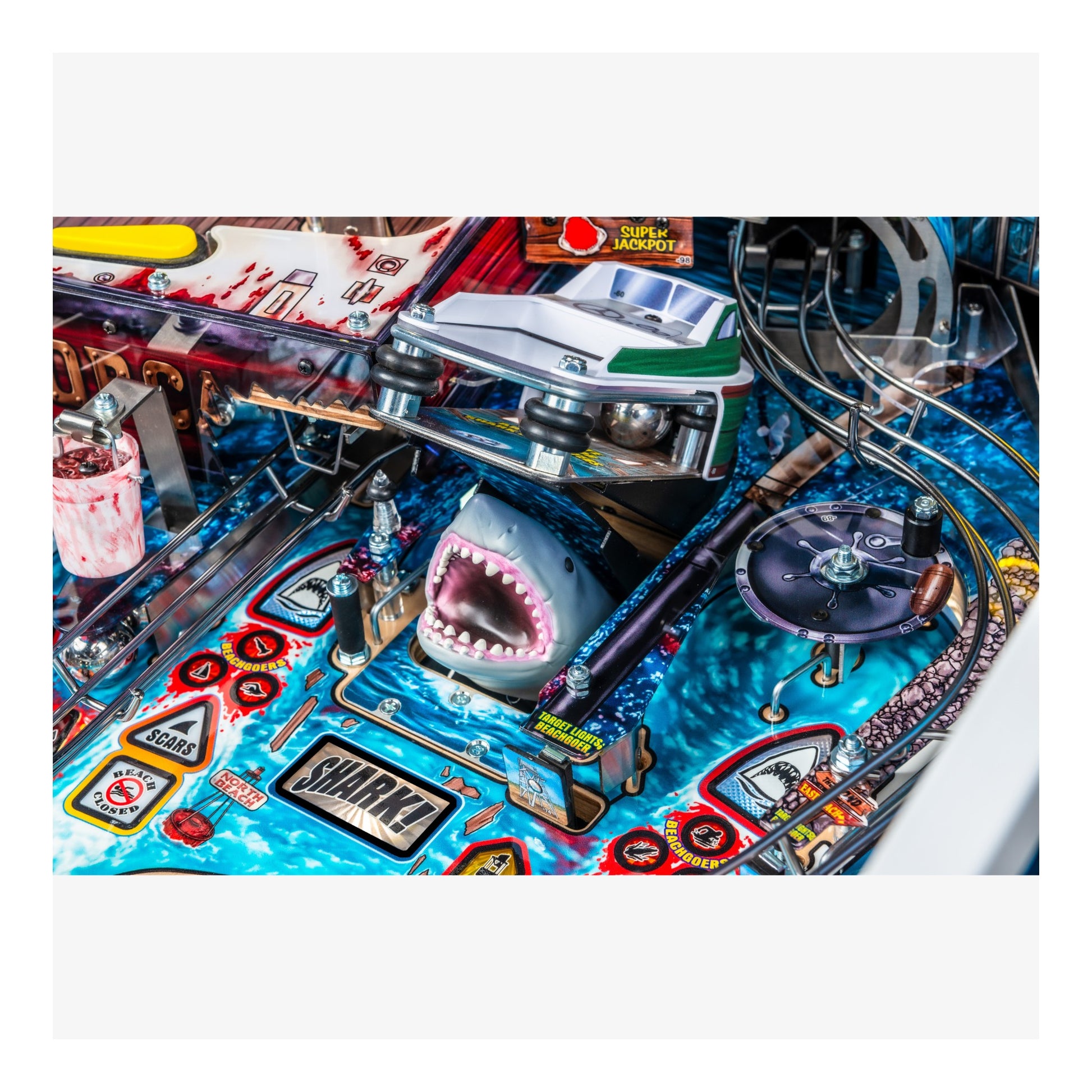 Close-up of a pinball machine with a shark design and colorful playfield.