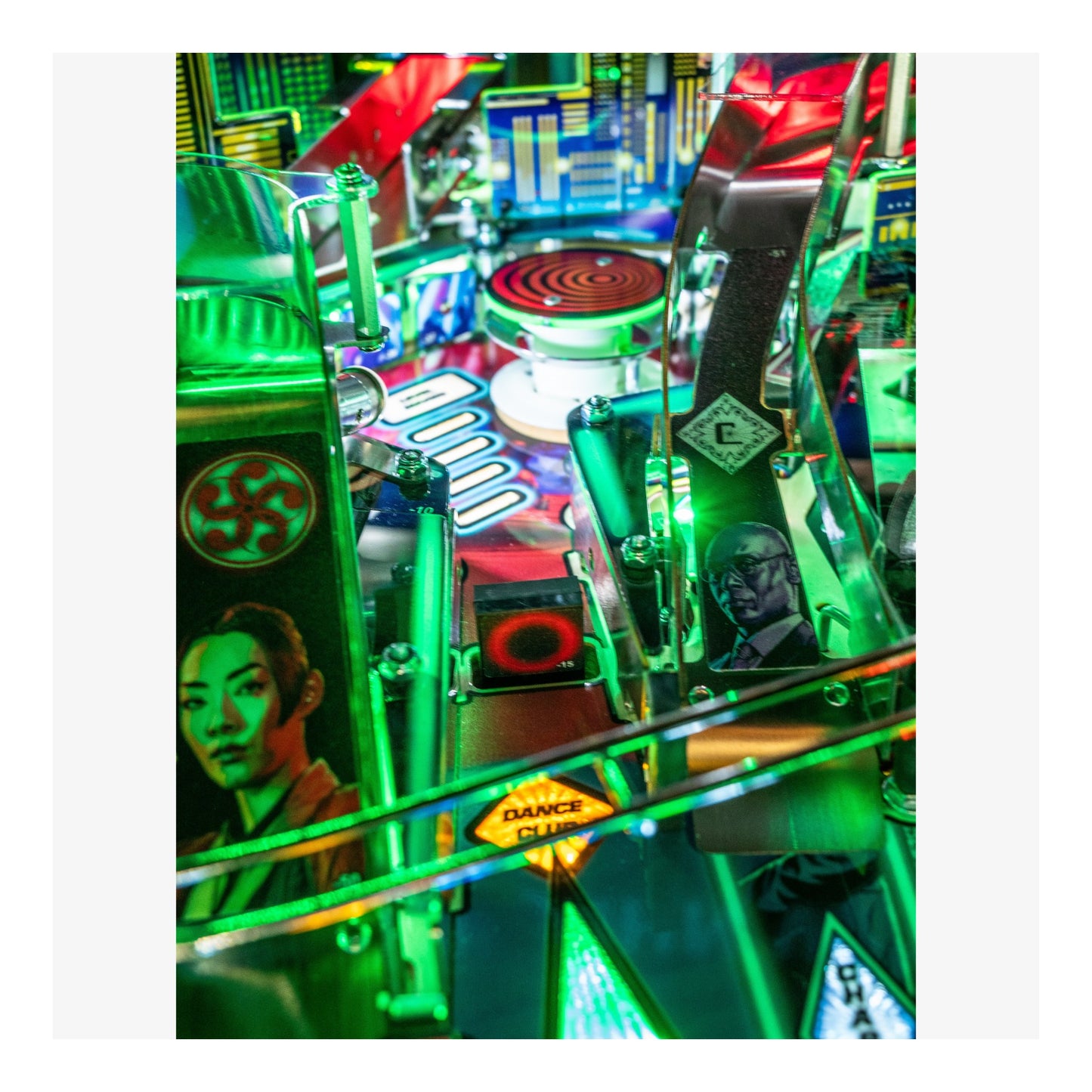 Close-up of a colorful pinball machine with vibrant green and red lights.