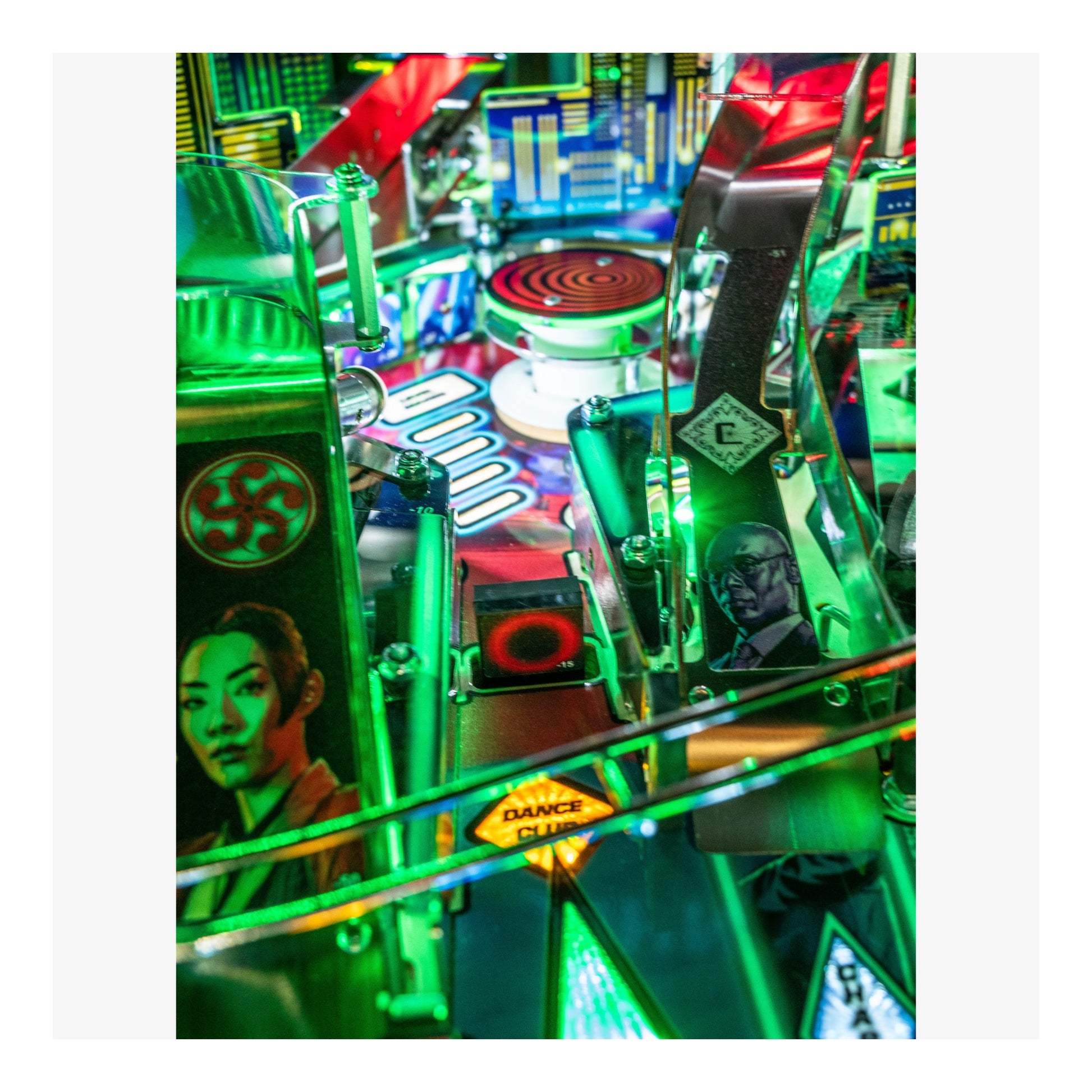 Close-up of a colorful pinball machine with vibrant green and red lights.