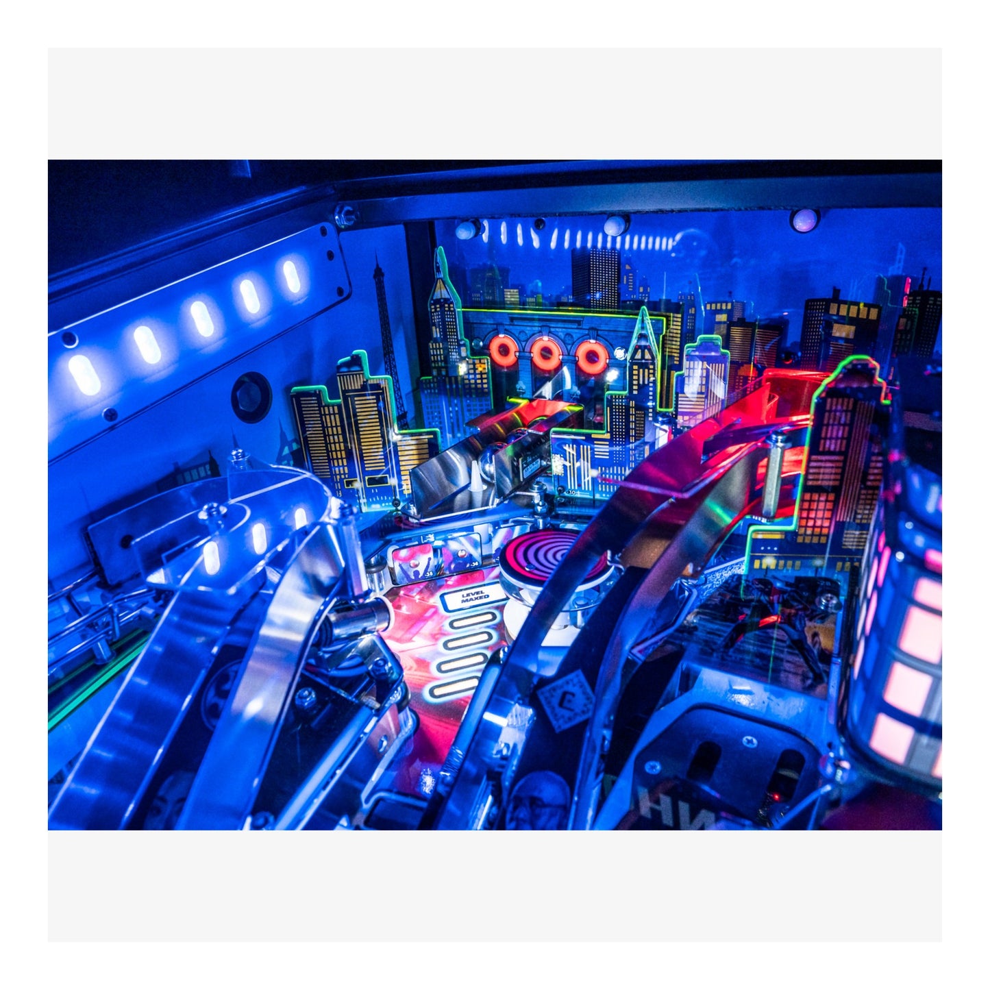 Close-up of a pinball machine with vibrant blue and red lighting