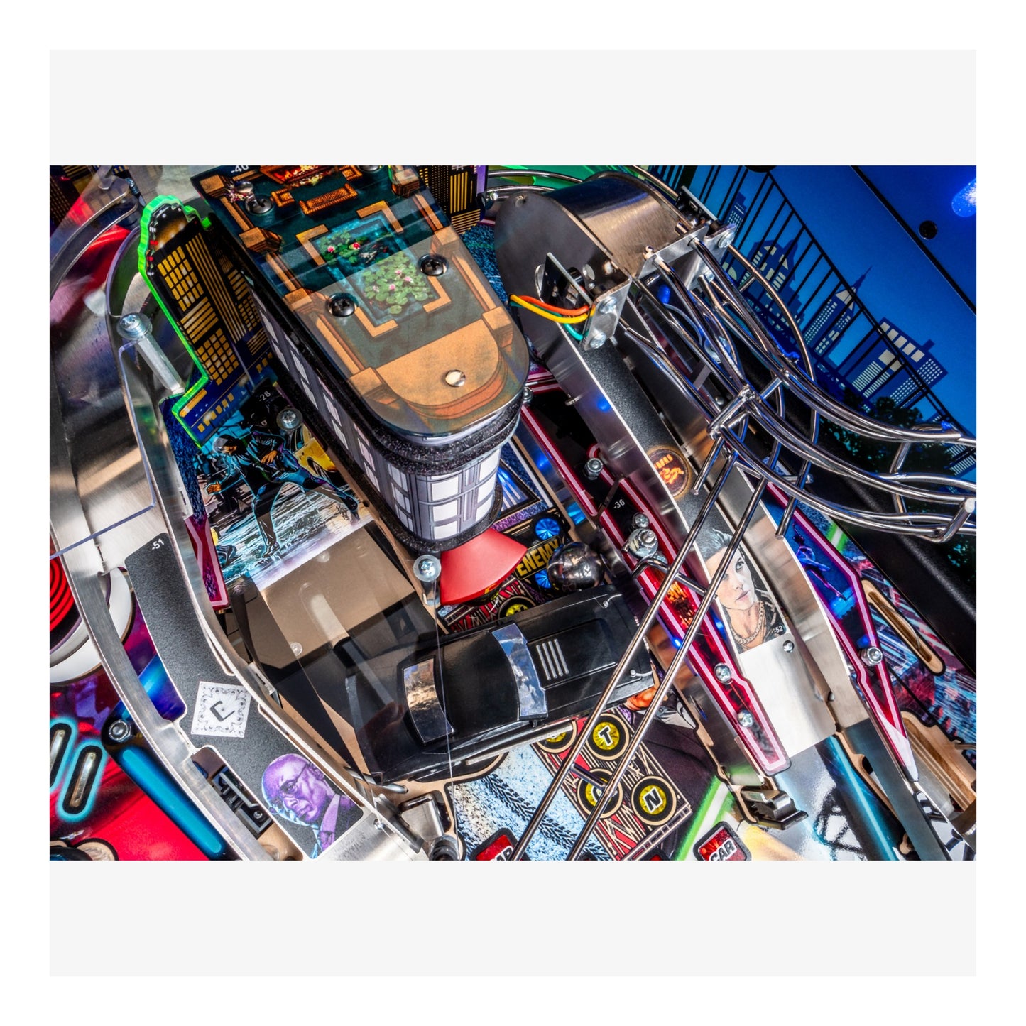 Close-up of a pinball machine with colorful components and a blue background