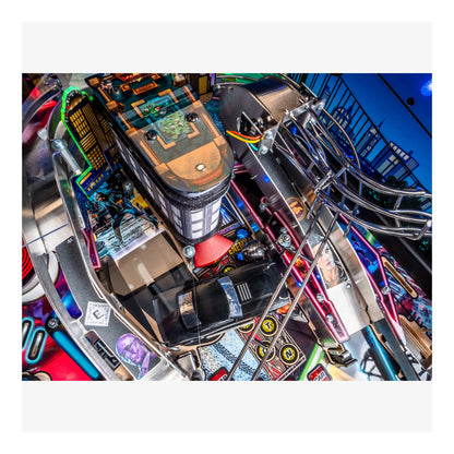 Close-up of a pinball machine with colorful components and a blue background