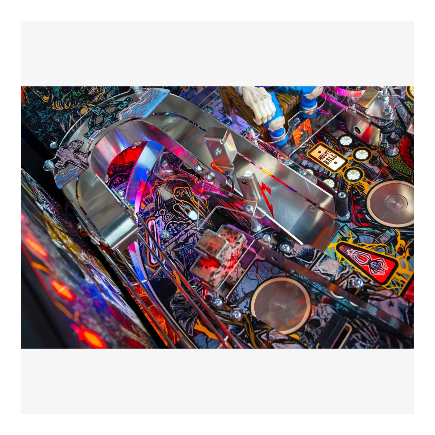 Close-up of a colorful pinball machine with various components and lights.