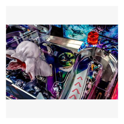 Close-up of a pinball machine with a shark figure and colorful playfield.