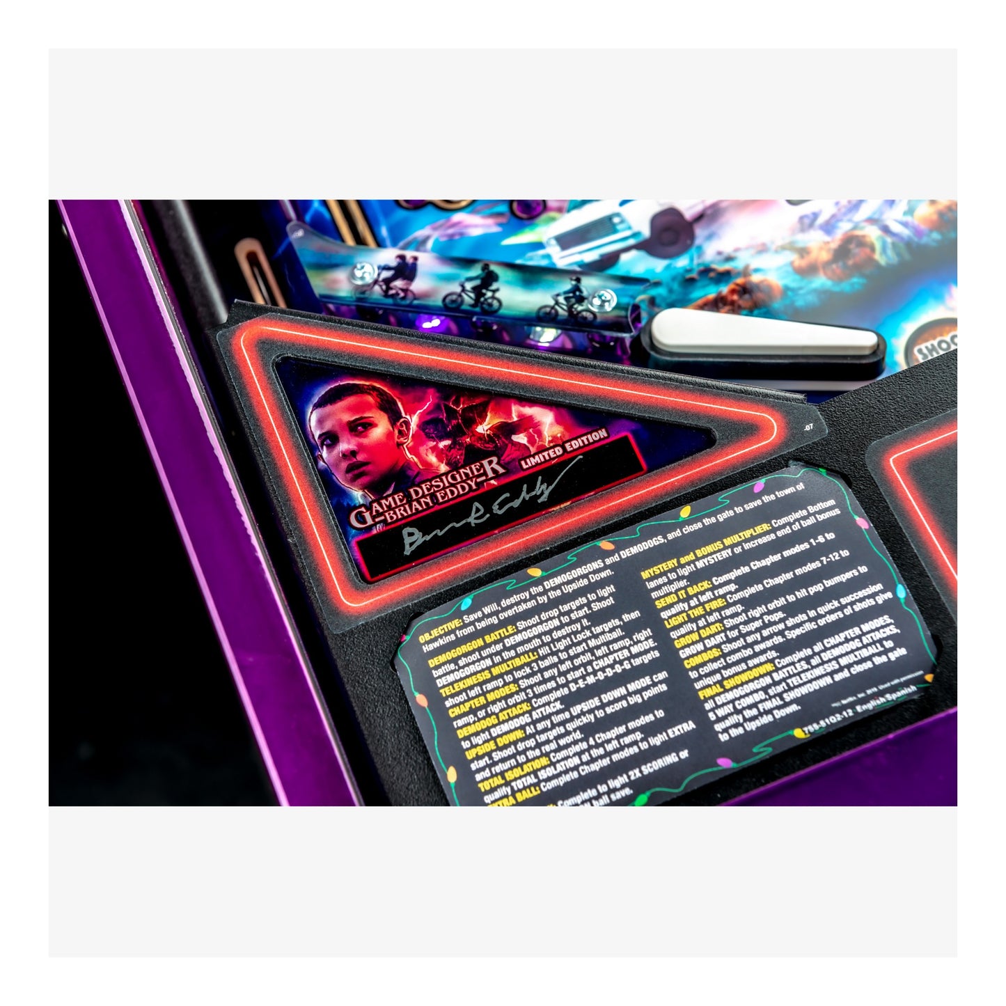 Close-up of a pinball machine with a player card and game details.